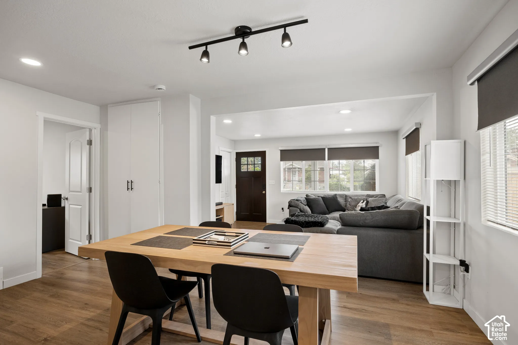 Open-concept interior featuring wood-finish flooring, recessed lighting, and a matte black three-light track fixture
