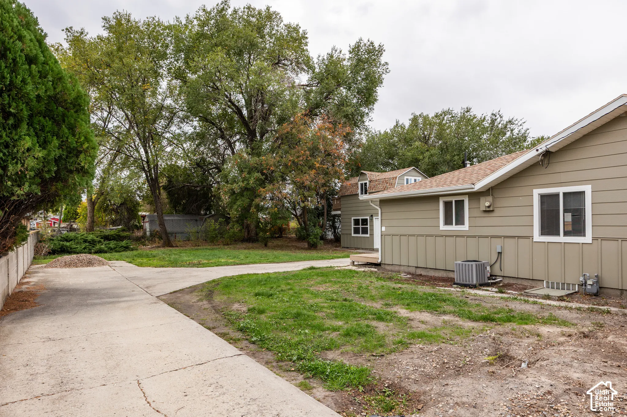 Exterior featuring horizontal siding, a concrete driveway, a detached secondary structure, and mature trees