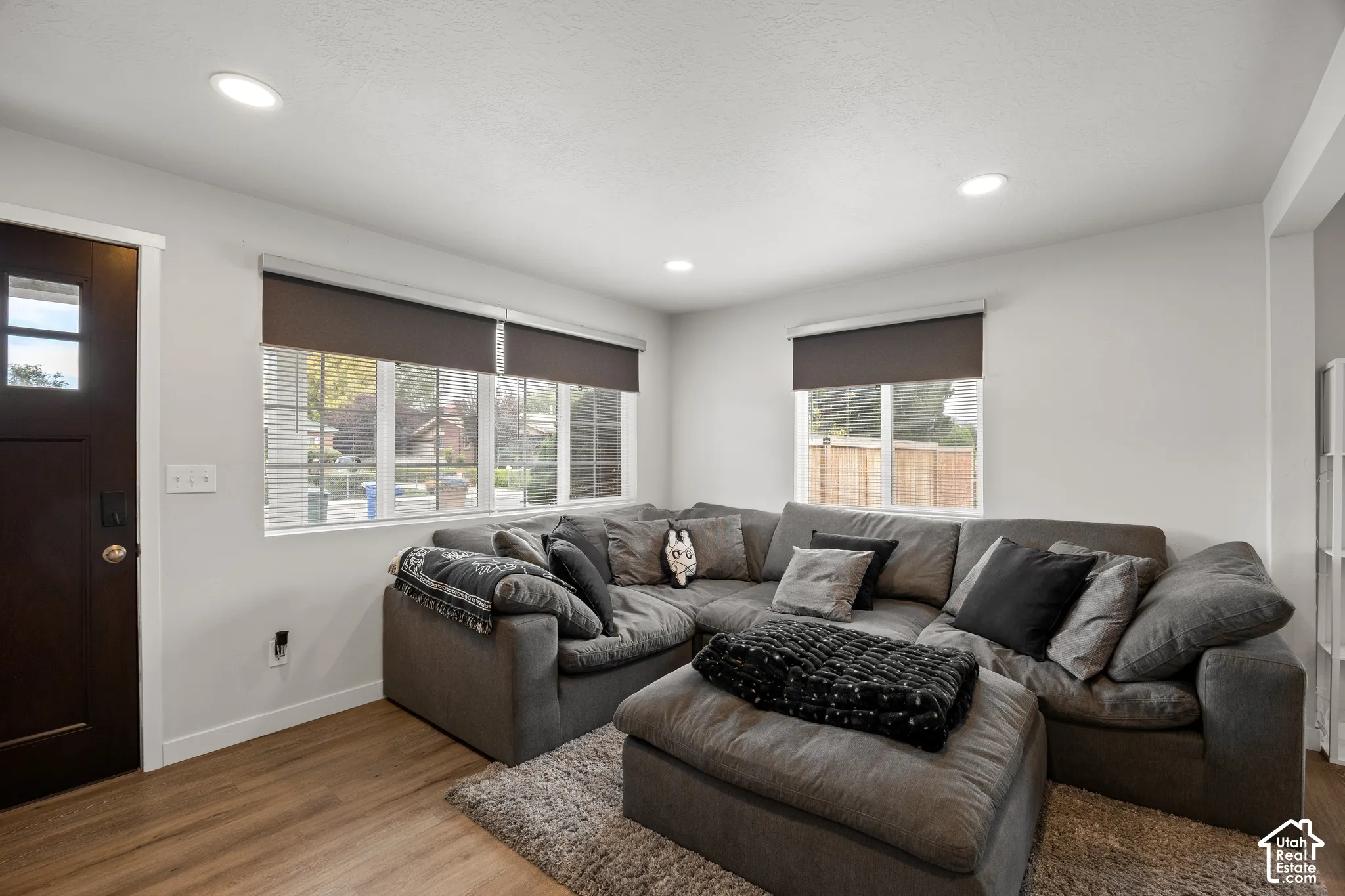 Wood-finish flooring, recessed lighting, multi-pane windows, and a dark-finish entry door with glass pane inset