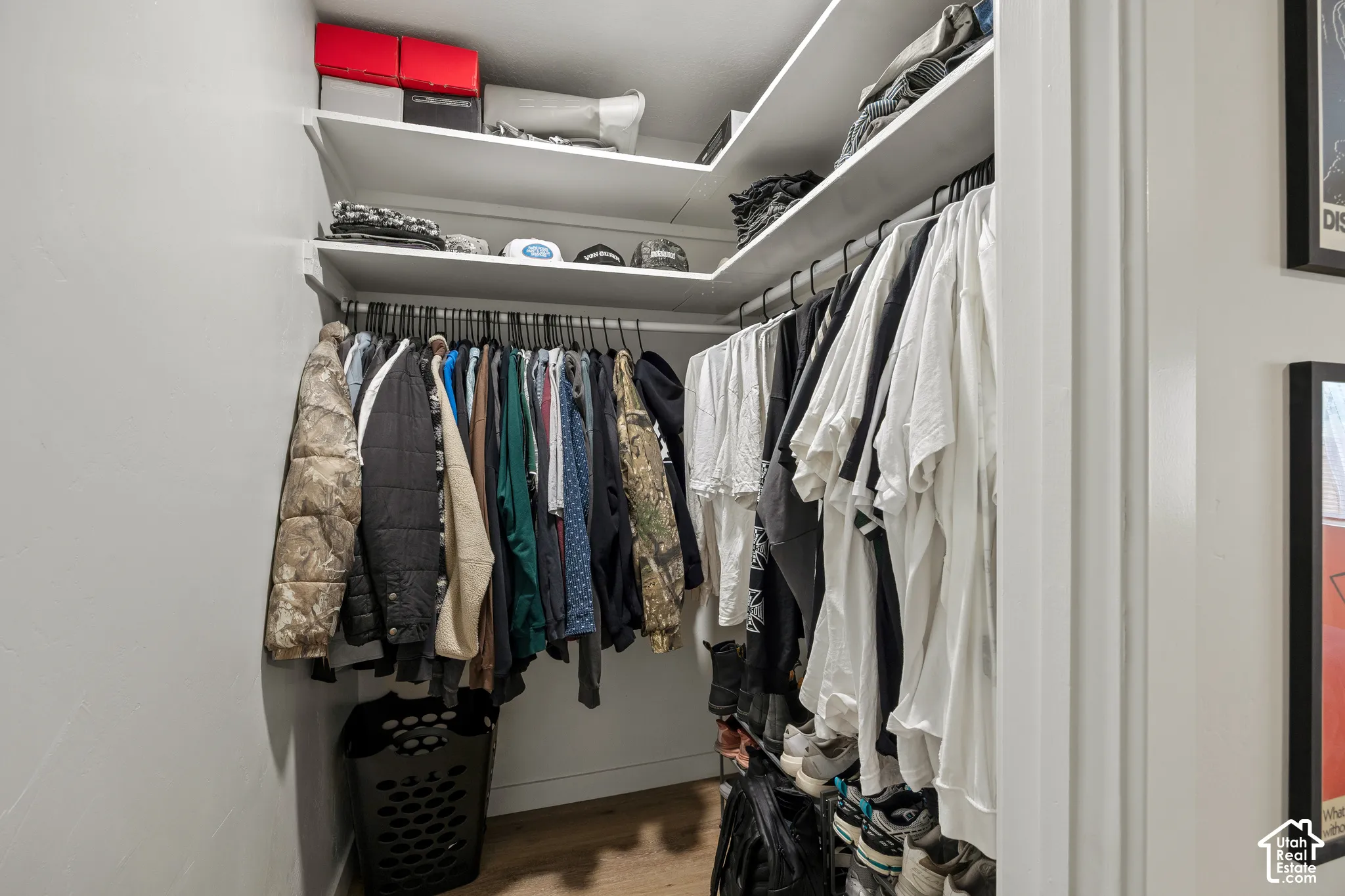 Walk-in closet featuring multi-level built-in shelving and integrated hanging rods with wood-finish flooring