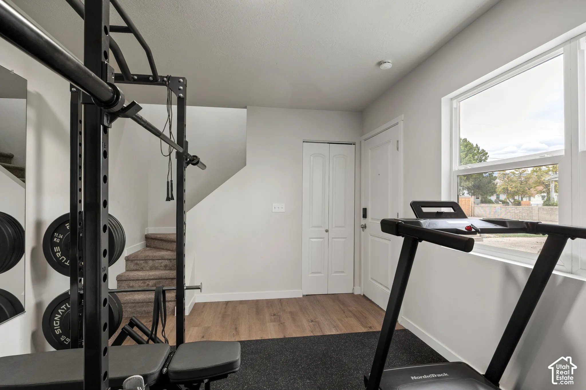 Neutral interior space featuring wood-finish flooring, a large window with natural light, and a dedicated closet with bifold doors