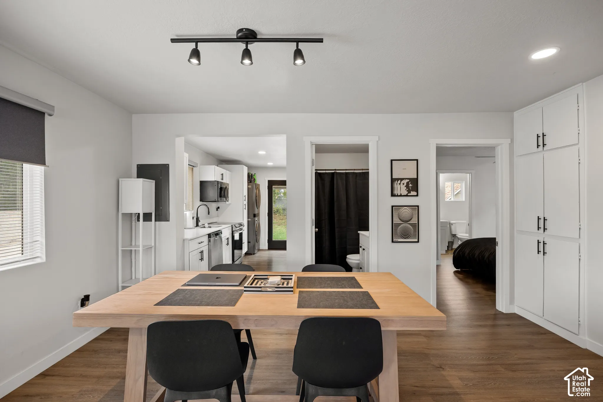 Wood-finish flooring, full-height built-in white cabinetry, and matte black triple-head track lighting