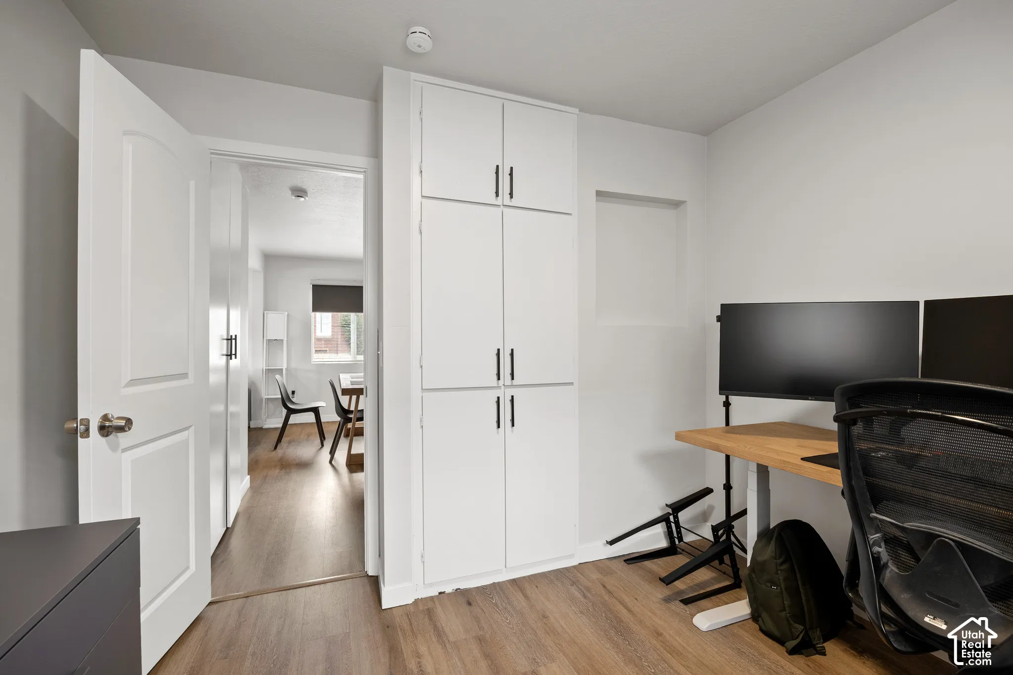 Built-in full-height storage cabinetry with matte black hardware, wood-finish flooring, and a recessed wall niche