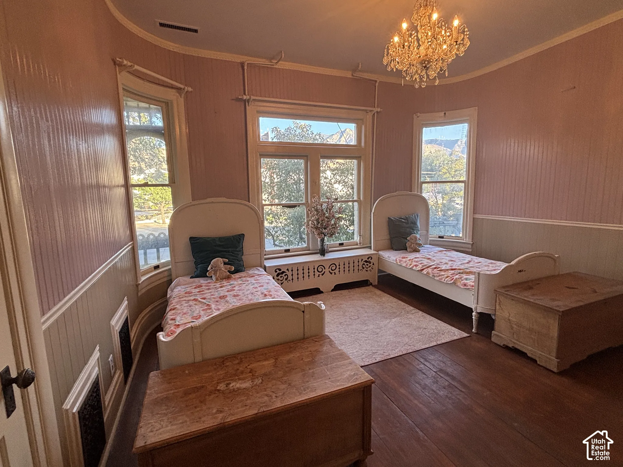 Room featuring curved walls, wood-finish flooring, beadboard wall paneling, a crystal chandelier, and a decorative metal radiator cover