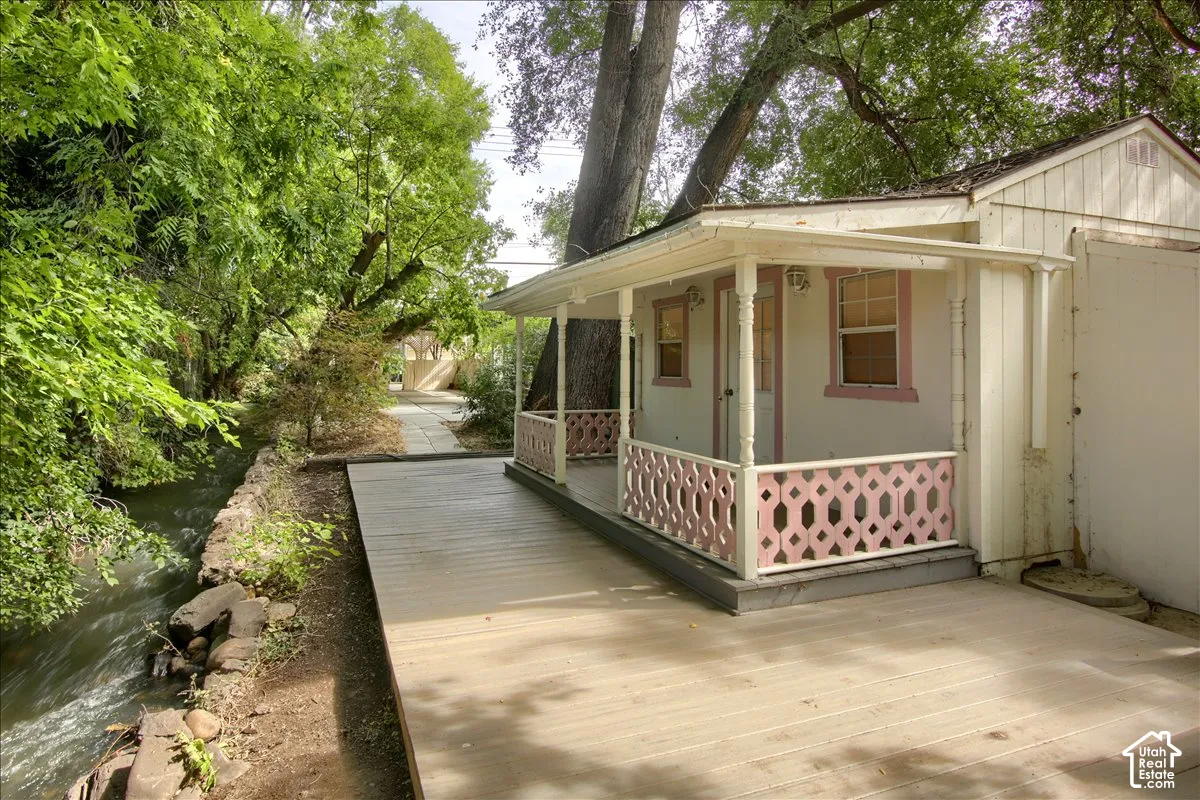 Casita exterior structure featuring a covered porch with decorative railing, wood-surface decking, and stone-bordered creek frontage