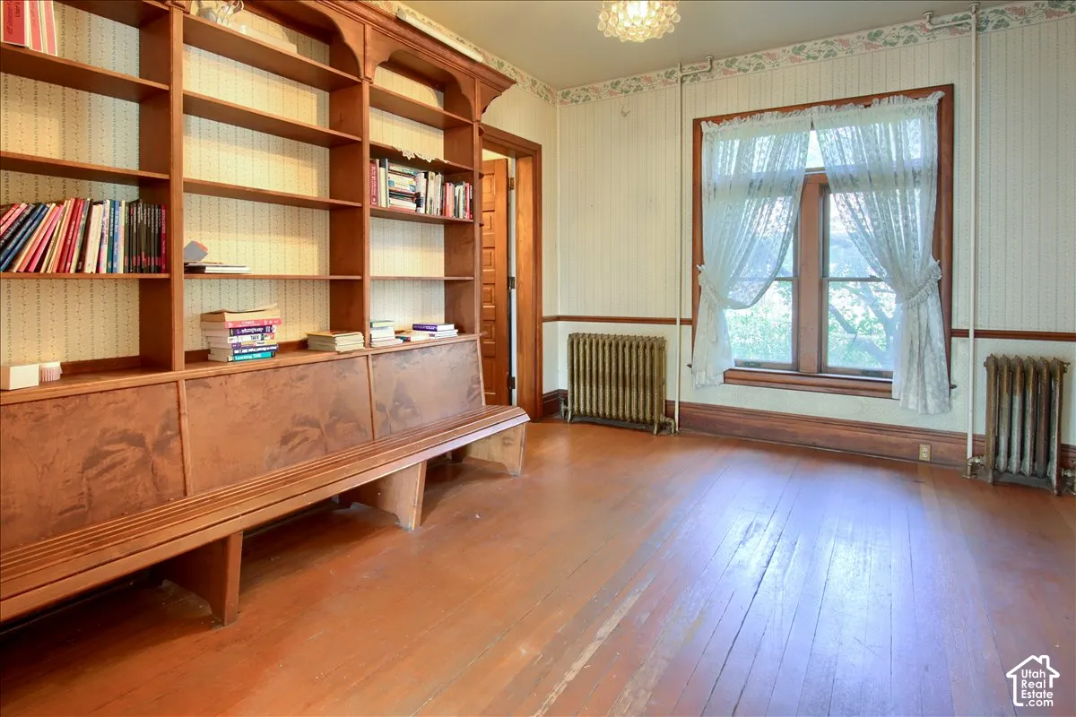Built-in floor-to-ceiling wood shelving, hardwood flooring, dual cast-iron radiators, and wood-framed window trim