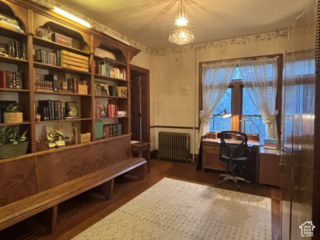 Floor-to-ceiling custom wood shelving with integrated bench seating, multi-pane windows, crystal chandelier, and cast-iron radiator