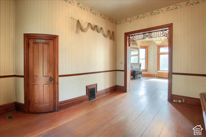 Interior space featuring natural wood-finish flooring, original stained wood door with detailed paneling, and intricate decorative wood fretwork above the arched doorway