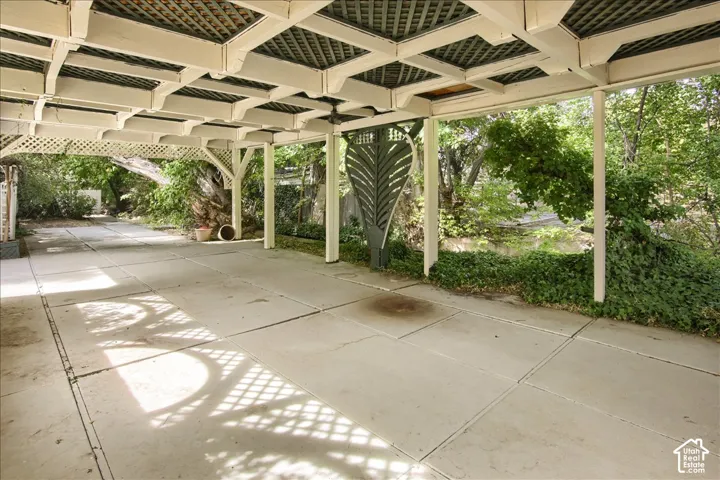 Covered patio featuring a concrete slab surface, a decorative wood pergola with lattice detailing, and vertical support posts