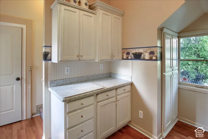 Built-in cabinetry featuring beadboard detailing, light-toned speckled countertops, and an integrated floor-to-ceiling storage pantry