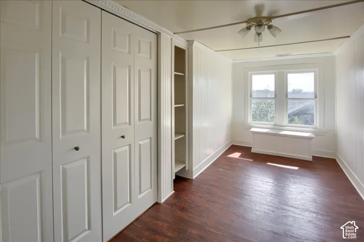 Room featuring wood-finish flooring, floor-to-ceiling built-in storage cabinets, custom beadboard wall paneling, and an integrated built-in window seat