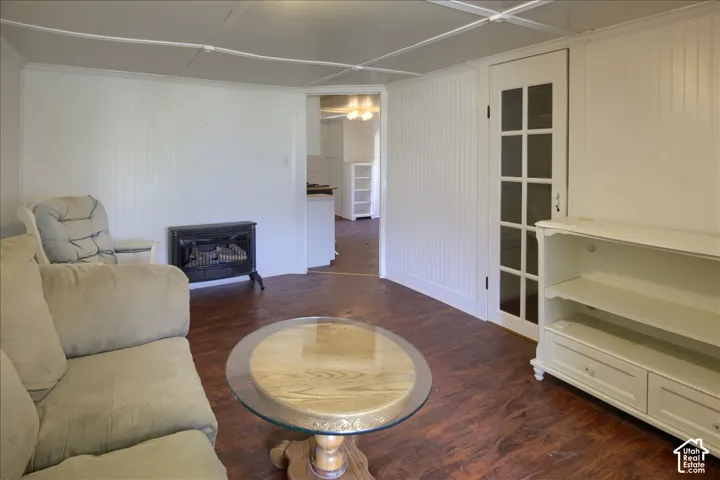 Interior space featuring beadboard wall paneling, wood-finish flooring, a freestanding heating stove, and a glass-paneled interior door