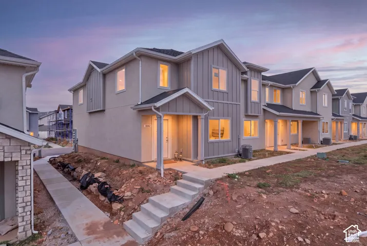 Modern two-story exterior featuring board-and-batten siding, multi-gabled roofline, covered front entry, and concrete walkway