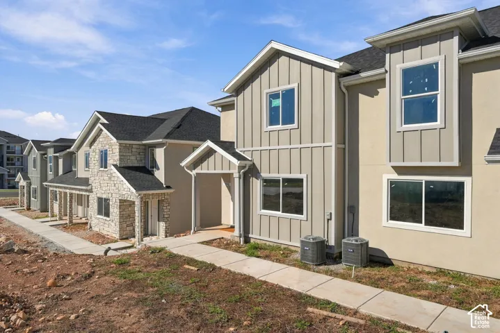 Multi-unit exterior featuring board-and-batten siding, stone veneer accents, asphalt shingle roofing, and concrete walkways