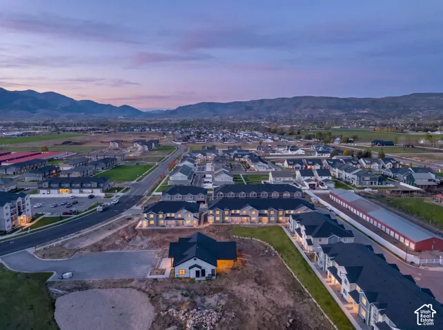 Aerial perspective of a multi-unit residential community featuring asphalt shingle roofing, multi-level structures, paved private driveways, and mountain range scenery