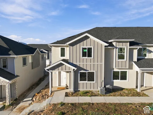 Multi-level exterior featuring vertical board-and-batten siding, contrasting stucco finish, dark shingle roofing, and a covered front entryway