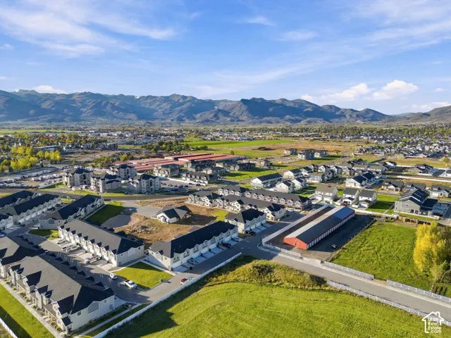 Aerial perspective featuring multi-family residential structures, paved roadways, managed green space, and a mountainous backdrop