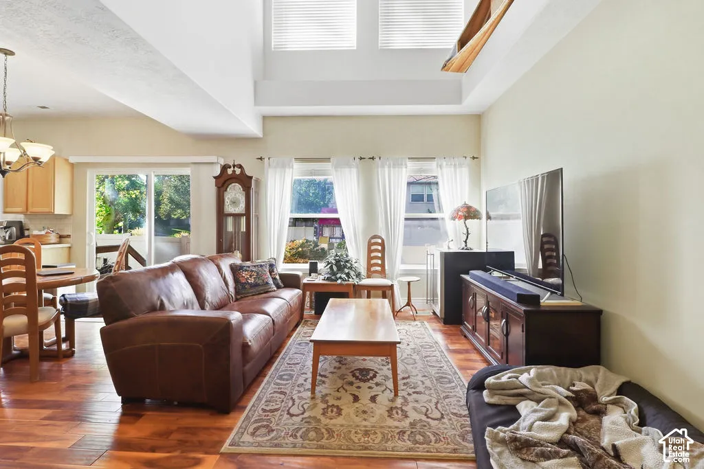 Living area featuring a double-height vaulted ceiling, wood-finish flooring, and expansive windows providing natural light
