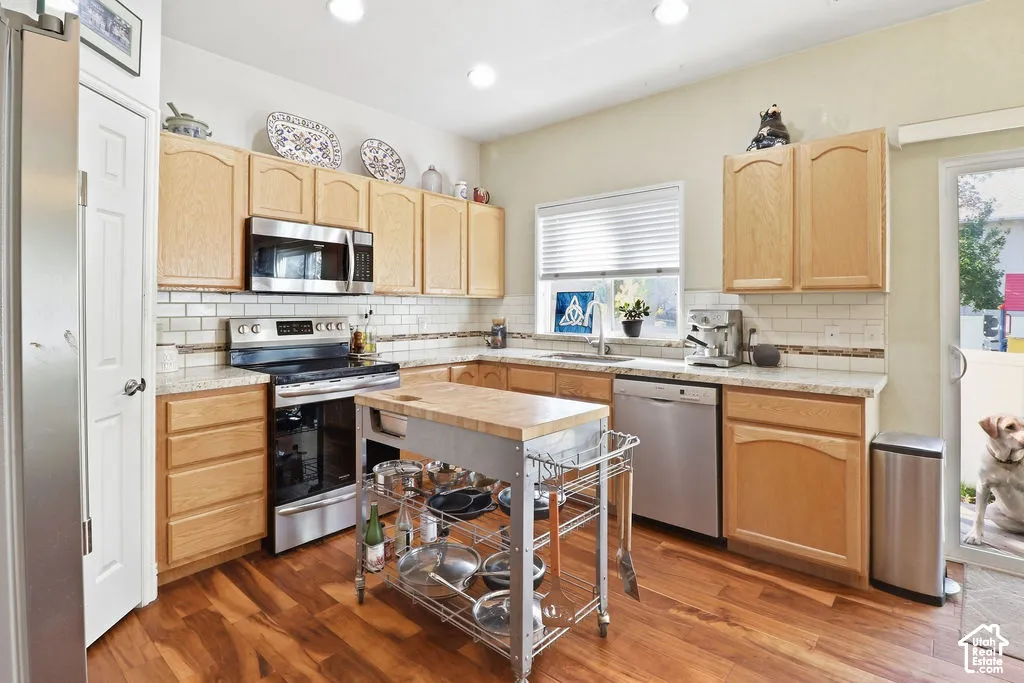 Kitchen featuring wood cabinetry, stone-finish countertops, subway tile backsplash, recessed lighting, and wood-finish flooring