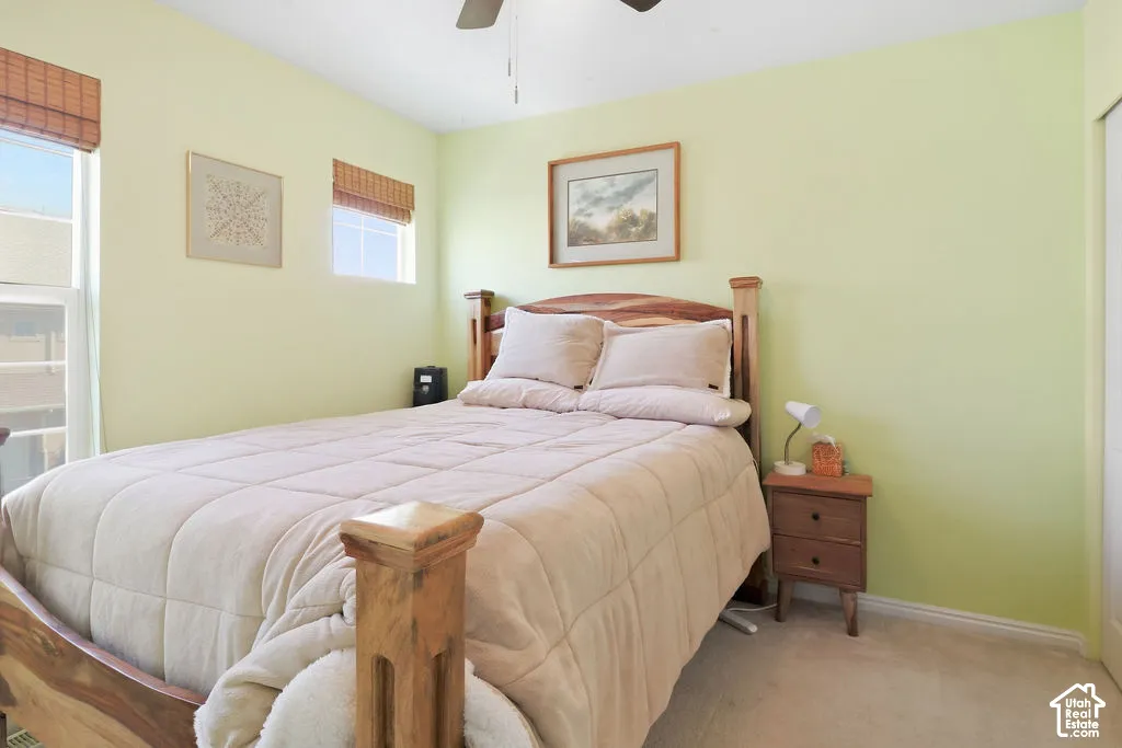 Bedroom featuring carpeted flooring, dual pane windows with bamboo shades, and a ceiling-mounted fan