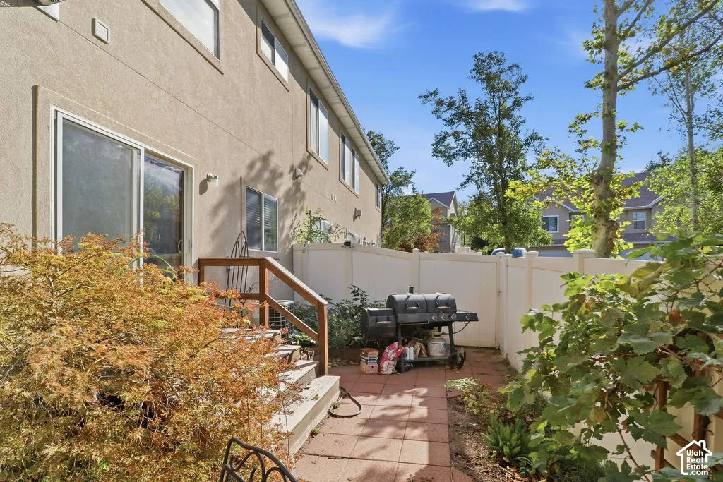 Rear exterior featuring a brick-paver patio, wood-finish stairs with a railing, and a private vinyl privacy fence