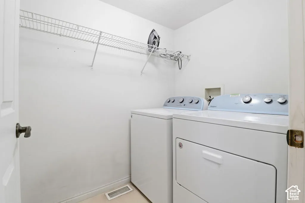 Dedicated utility space featuring installed white laundry appliances and wall-mounted wire shelving