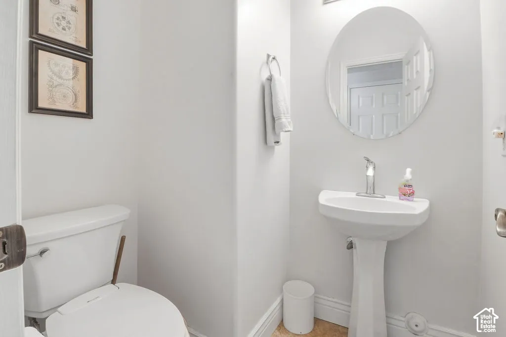 Pedestal sink with a single-handle faucet, oval wall-mounted mirror, and wall-mounted towel ring