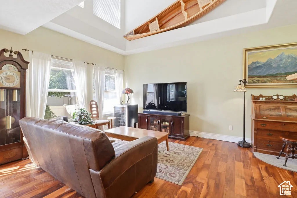 Vaulted ceilings with recessed architectural detail, wood-finish flooring, and expansive windows