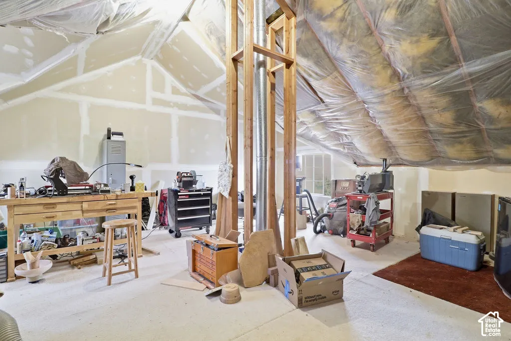 Unfinished attic space featuring vaulted ceilings, drywall paneling, and an exposed metal chimney flue