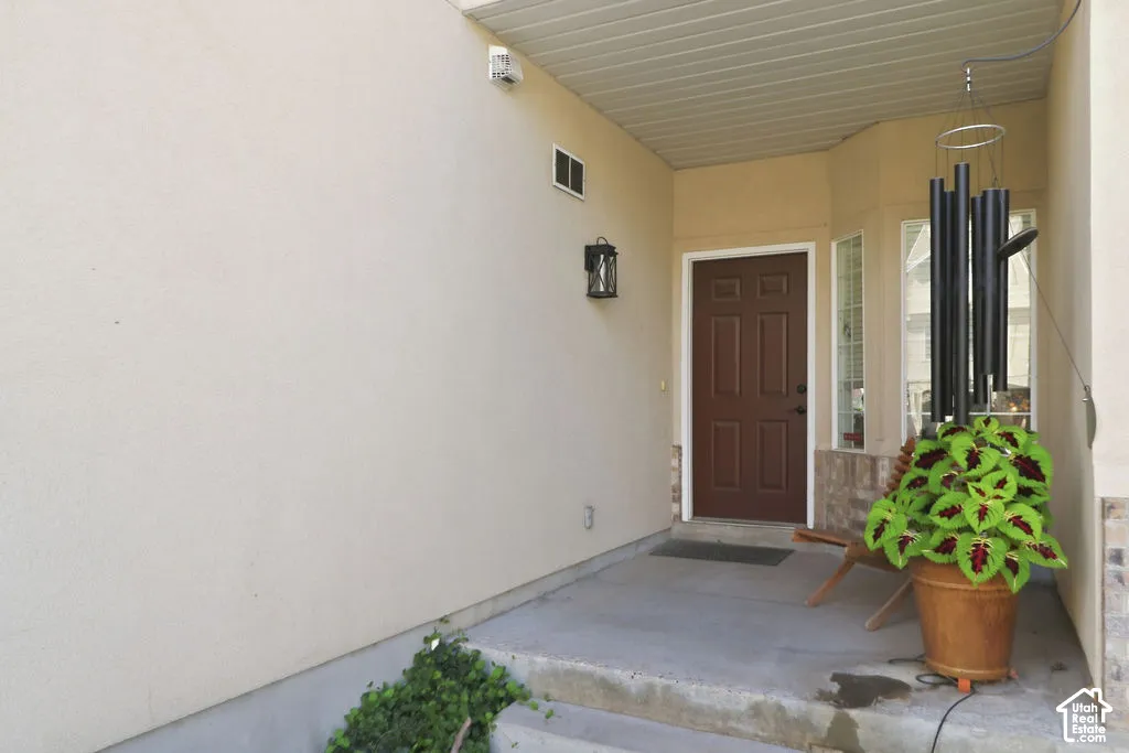 Covered entryway featuring smooth stucco exterior walls, stone veneer accents, recessed soffit lighting, and a paneled entry door