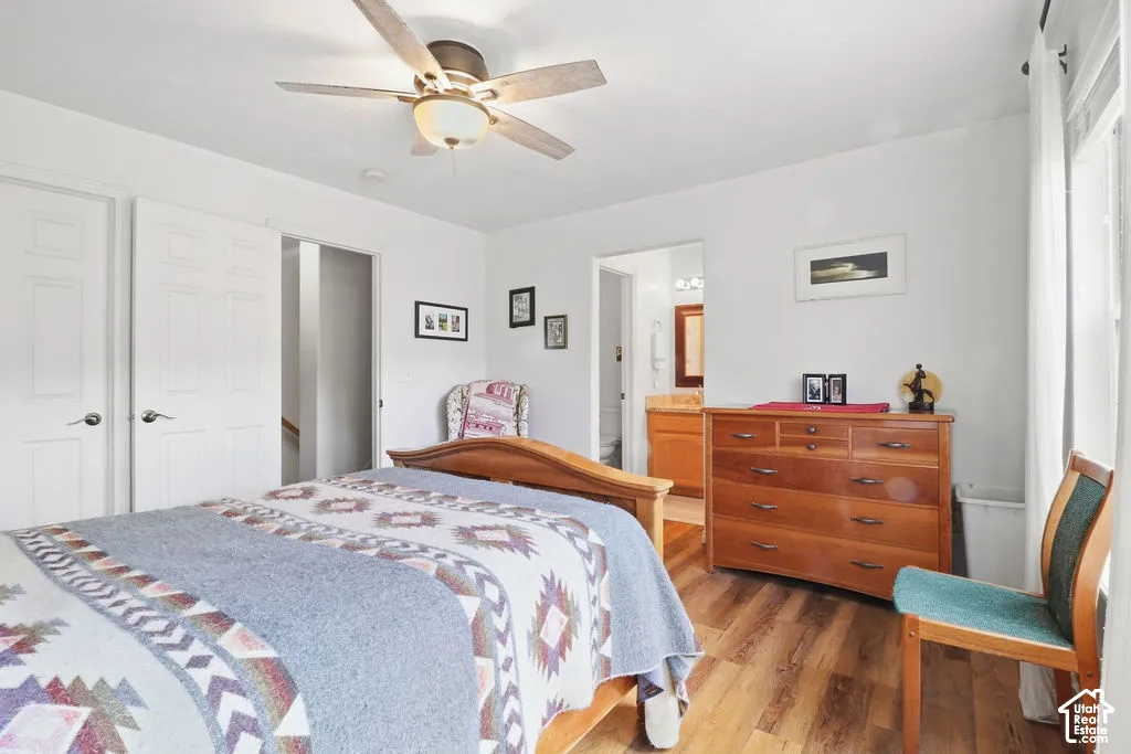 Room interior featuring wood-finish flooring, a ceiling fan with integrated light fixture, and two-panel interior doors