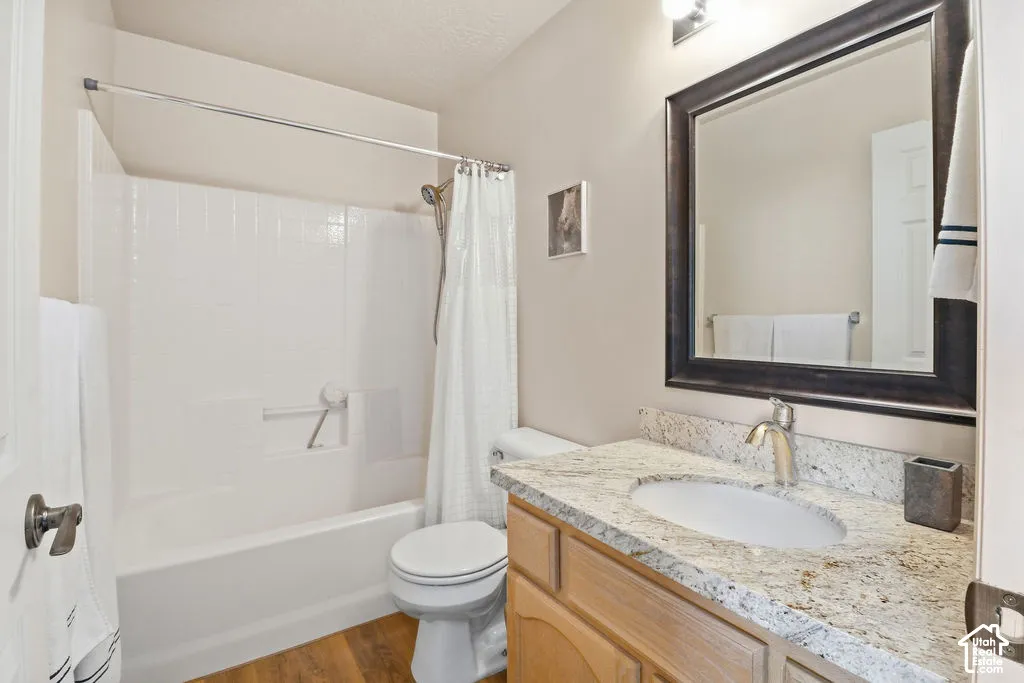 Bathroom featuring a vanity with stone countertop, undermount sink, dark-frame wall mirror, and a tub-shower combination with tile surround