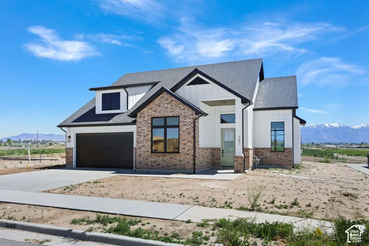 Modern farmhouse-style exterior featuring a dark asphalt shingle roof, white vertical siding, and brick accents