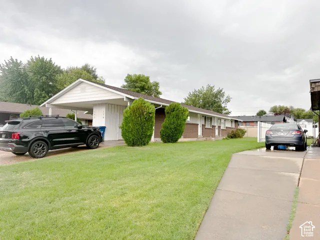 Single-story residence featuring a brick exterior, gabled roofline, covered carport, and concrete driveway