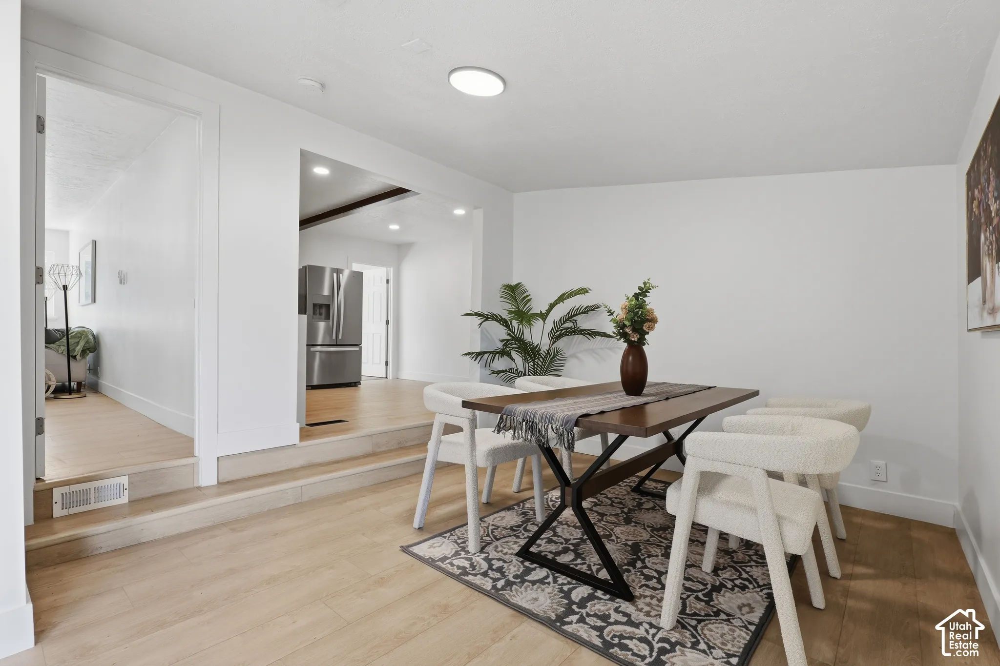 Open-concept area featuring light-toned wood-finish flooring, recessed lighting, and a multi-level floor plan with step-up access