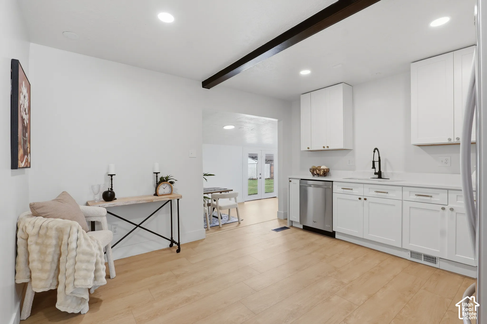 Kitchen featuring white shaker-style cabinetry, stainless steel dishwasher, wood-finish flooring, recessed lighting, and an exposed ceiling beam