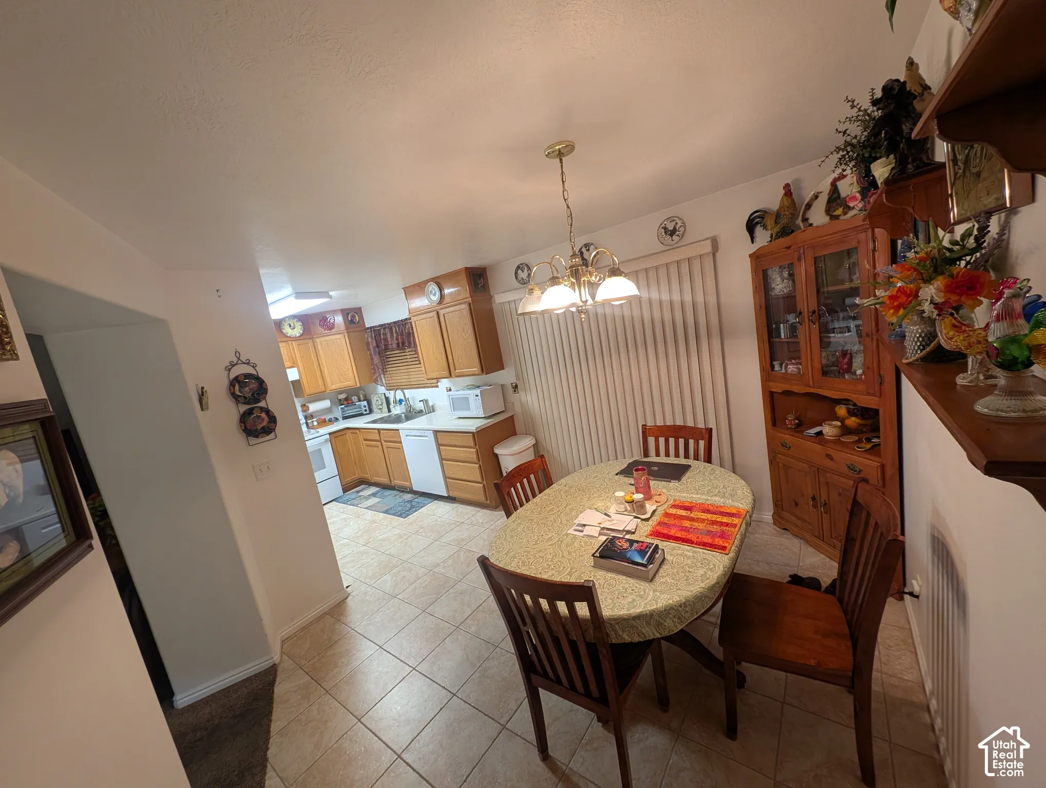 Kitchen and dining area featuring wood cabinetry, tile flooring, built-in china hutch, and a multi-arm brass chandelier