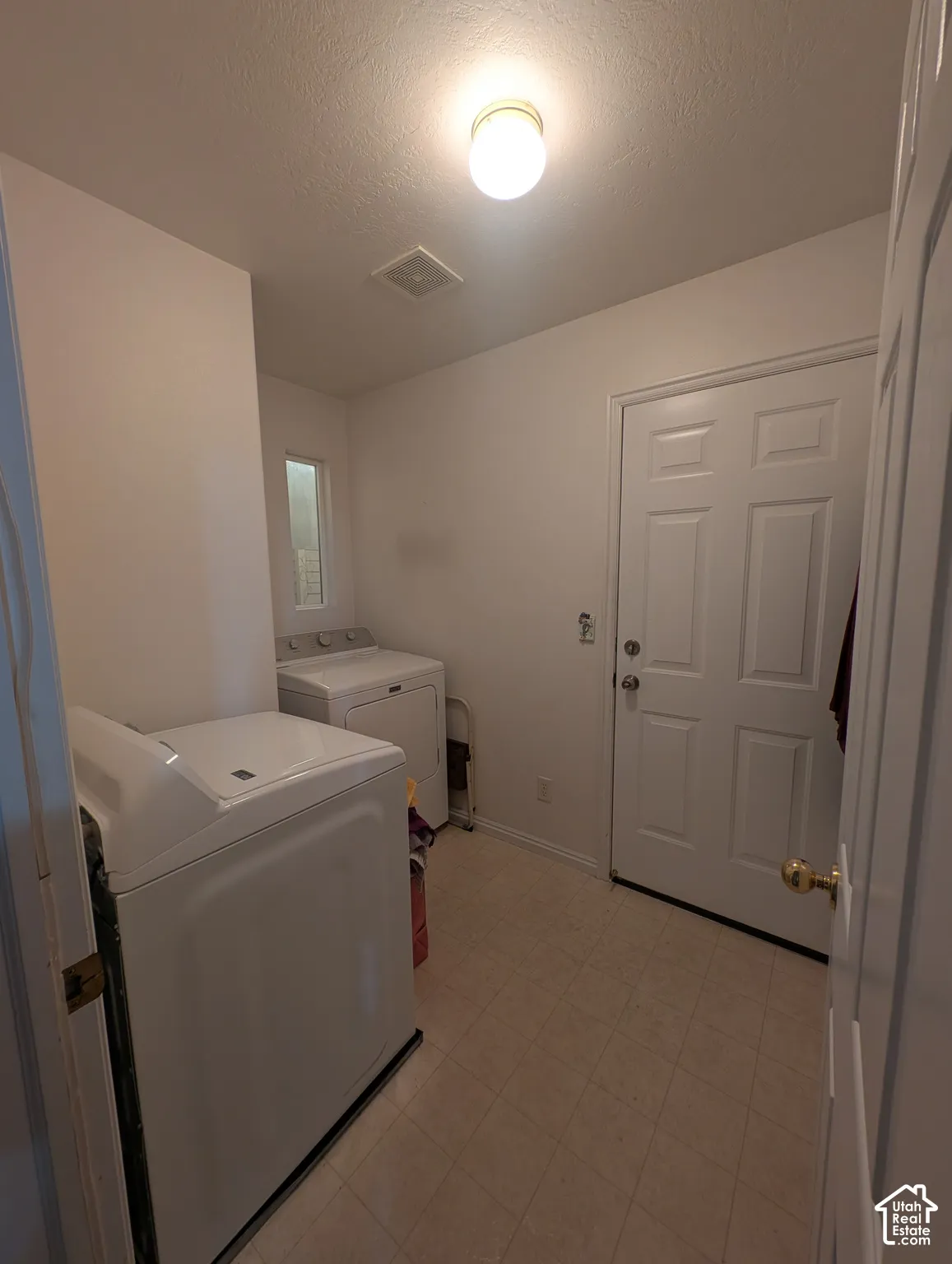Dedicated utility space featuring resilient vinyl tile flooring, a six-panel exterior door, and a flush-mount circular ceiling fixture