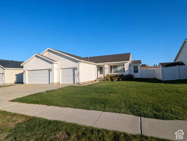 Single-story exterior featuring white vinyl siding, a dual-bay garage, a shingled roof, and a fenced side yard