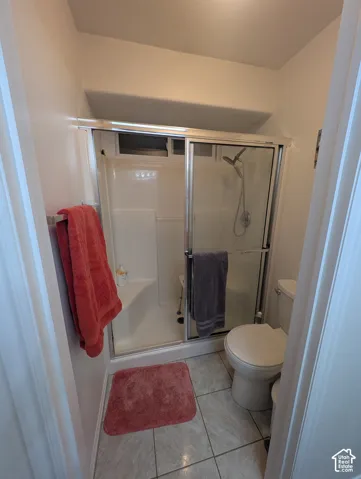 Shower stall featuring a glass-panel sliding door, built-in corner seat, and handheld shower fixture, complemented by tile flooring