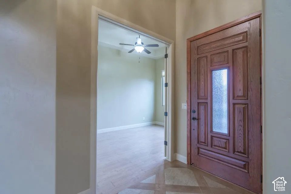 Entryway featuring a solid wood door with a decorative glass panel, stone-tile flooring with an inlaid pattern, and a high ceiling