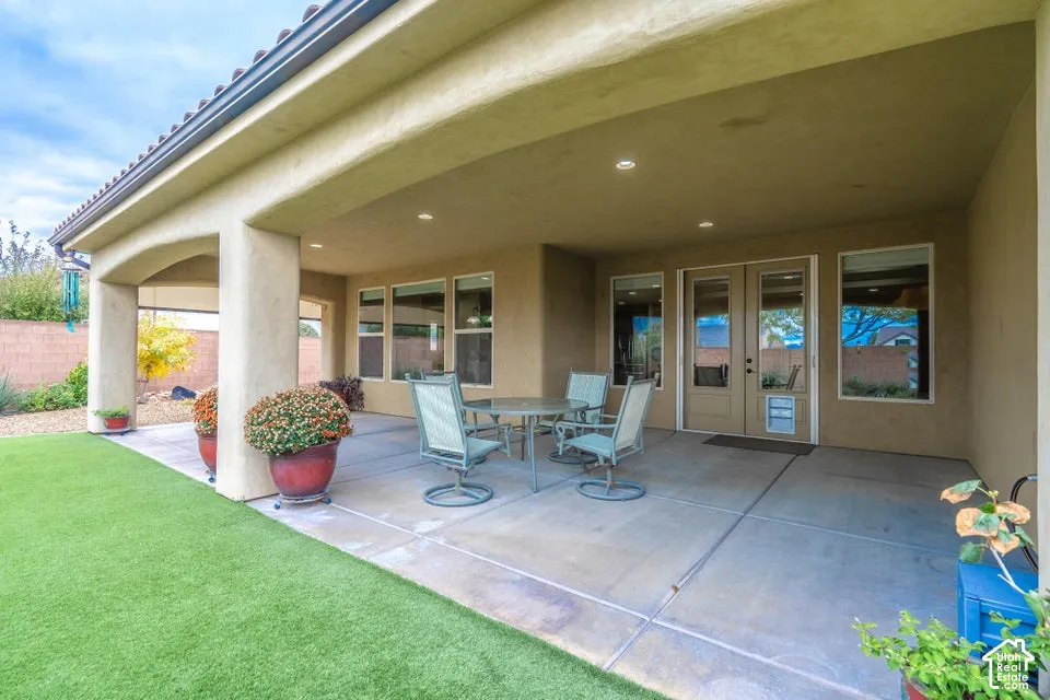 Covered rear patio featuring a concrete floor, recessed lighting, stucco support pillars, and double-door entry