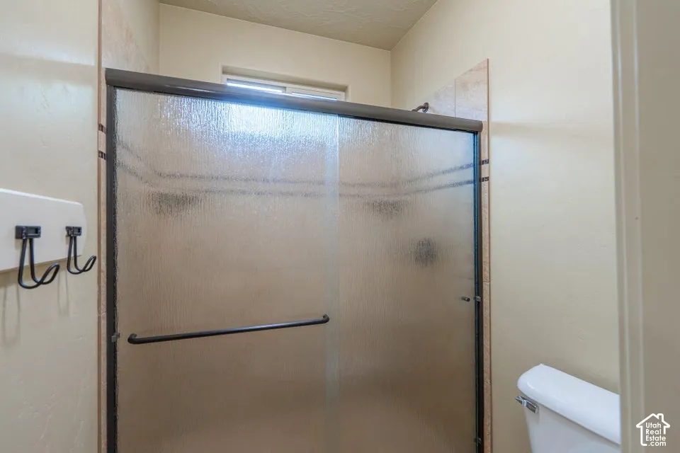 Shower enclosure featuring a sliding glass door with dark metal framing, tiled wall surround with decorative accent banding, built-in recessed soap niches, and an upper window