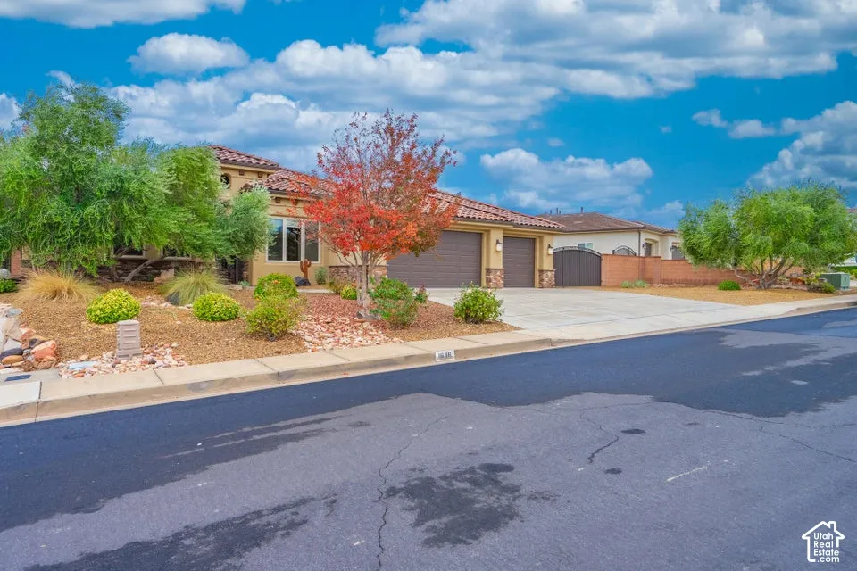 Single-story residence featuring a tile roof, stucco exterior, stone masonry accents, a paved driveway, and an attached three-car garage