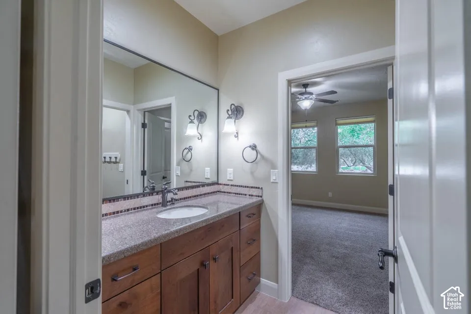 Bathroom vanity featuring stained wood cabinetry, a stone-composite countertop with an integrated basin, a full-width mirror, and dual wall-mounted light fixtures with decorative glass shades