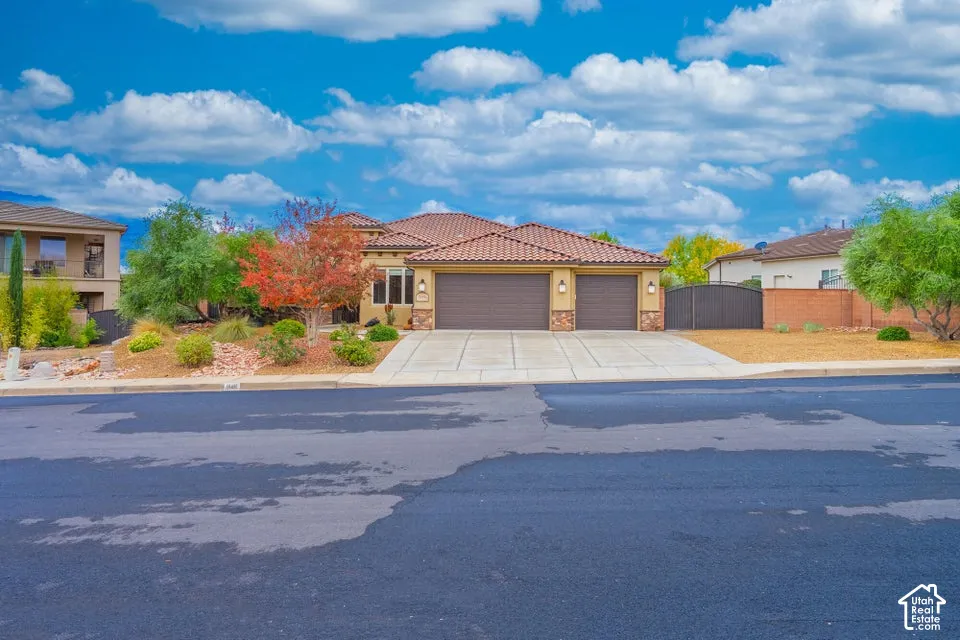 Single-story residence featuring a tile roof, stucco exterior, three-car garage, concrete driveway, and gated side yard access