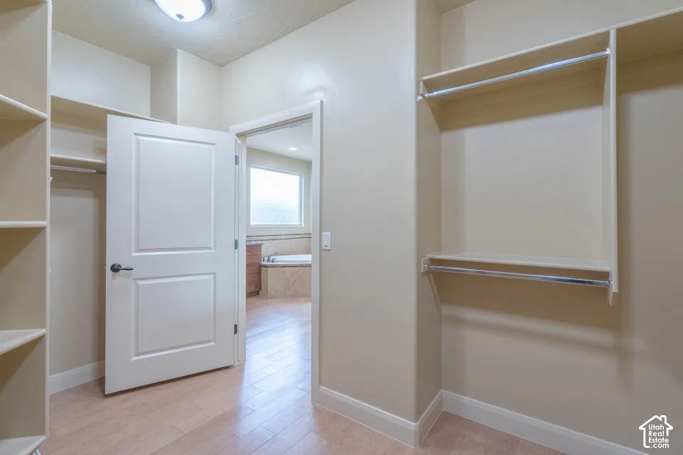 Walk-in closet featuring built-in shelving, hanging rods, wood-finish flooring, and a solid-core paneled door