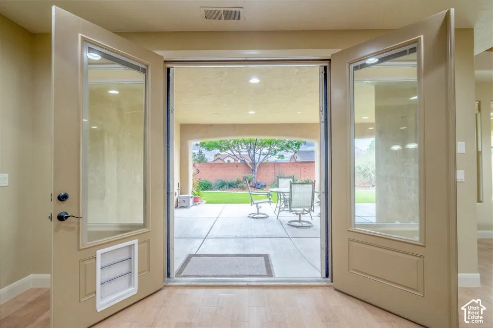 Double-door entry featuring glass panels, integrated pet door, wood-finish flooring, recessed lighting, and a covered patio with concrete flooring