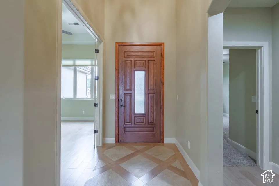 Entryway featuring high ceilings, a stained wood-finish front door with an inset frosted glass panel, and geometric tile flooring with wood-finish borders