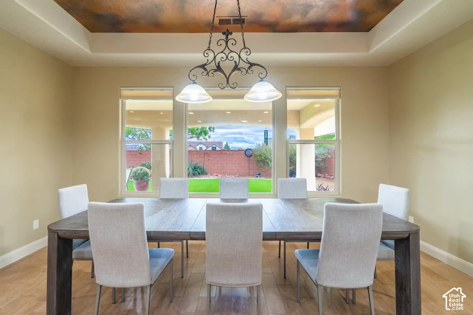 Tray ceiling with faux-finish detailing, decorative iron chandelier, and large windows providing natural light and exterior visibility